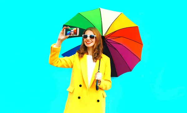 Счастливая Улыбающаяся Женщина Красочным Зонтиком Делает Селфи Смартфона Синем Фоне — стоковое фото