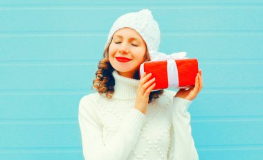 Noel, insanlar kavramı - gülümseyen kadın örgü şapka, kazak mavi arka plan üzerine hediye kutusu elinde tutar mutlu