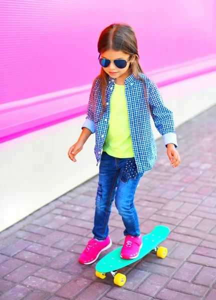 时尚的孩子小女孩在滑板上五颜六色的粉红色墙壁背景 — 图库照片