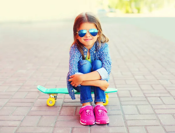 时尚的肖像快乐微笑的小女孩坐在城市街道上的滑板 — 图库照片