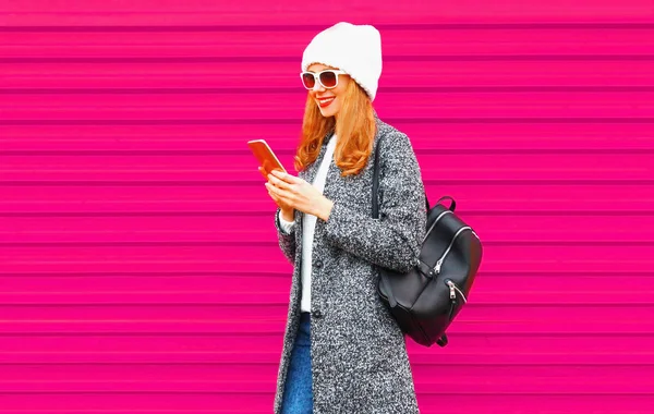 電話を着て女子生徒の笑顔幸せな若いコート ジャケット 街の通り カラフルなピンクの壁の背景の上を歩いてバックパック — ストック写真
