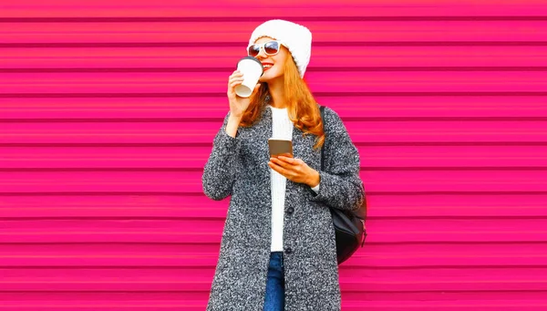 Jovem mulher bebe café segurando smartphone em colorido wa rosa — Fotografia de Stock