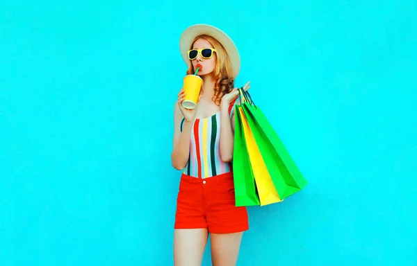 Elegante mujer bebiendo jugo sosteniendo bolsas de compras en t colorido —  Fotos de Stock