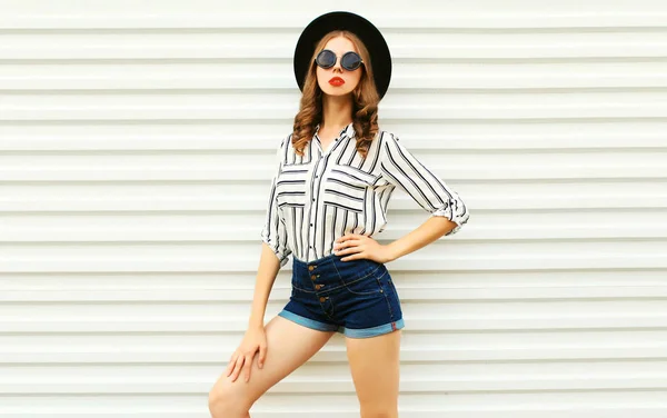 Stylish young woman model in black round hat, shorts, white stri — Stock Photo, Image