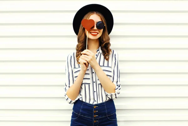 Retrato feliz joven sonriente ocultando su ojo con el corazón rojo —  Fotos de Stock