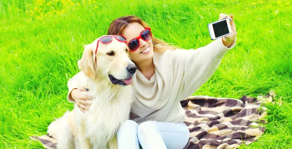 Щаслива жінка посміхається з золотою собакою ретрівер беручи селфі — стокове фото