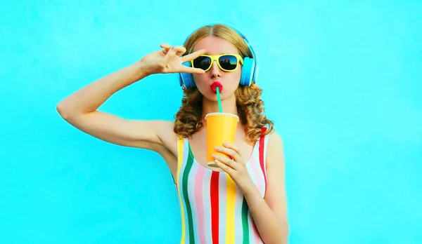 Portrait cool girl drinking fruit juice listening to music in wi
