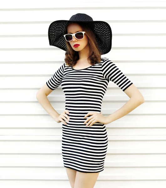 Stylish young woman in striped dress, summer straw hat posing on — ストック写真