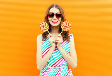 Kırmızı kalp şeklinde sunglas lolipop tutan mutlu gülümseyen kadın