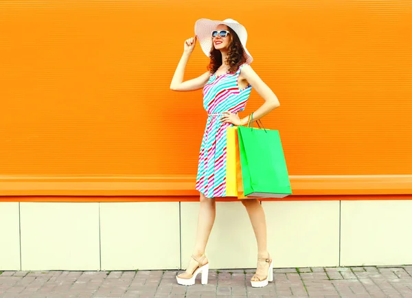 Κομψή χαμογελαστή γυναίκα με σακούλες για ψώνια φορώντας πολύχρωμη Ρίγα — Φωτογραφία Αρχείου
