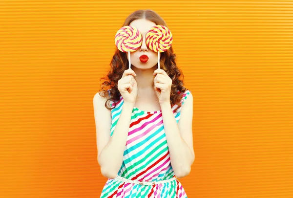 Retrato mujer feliz escondiendo sus ojos con dos piruletas, soplando — Foto de Stock