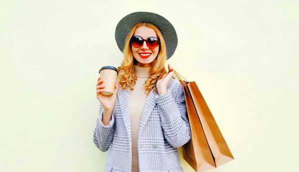 Portrét šťastné usměvavé ženy s nákupními pytli, držící kávu — Stock fotografie