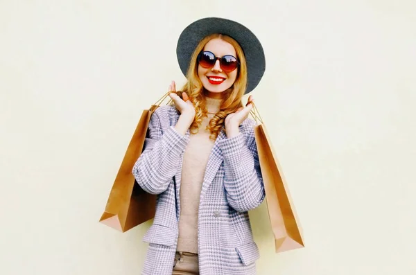 Портрет счастливой улыбающейся женщины с сумками для покупок в розовом пальто, — стоковое фото