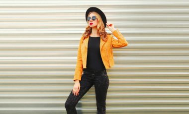 Sarı ceketli şık bir kadın modeli, siyah yuvarlak.