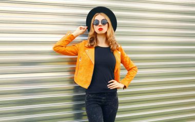 Sarı ceketli şık bir kadın modeli, siyah yuvarlak.