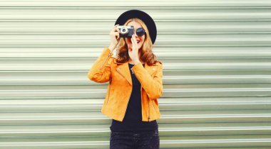 Retro kameralı şık gülümseyen kadın seni giyerken fotoğraf çekiyor.