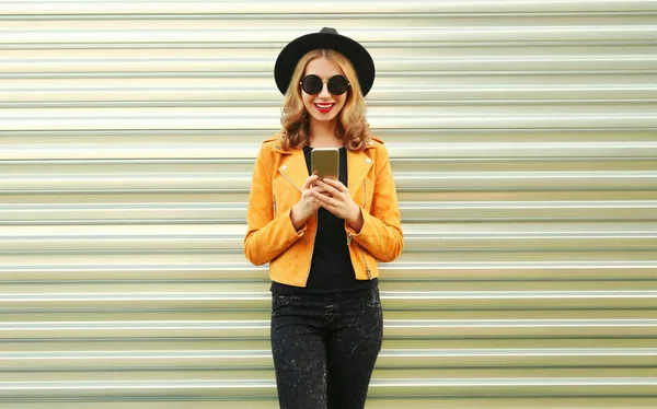 Mulher sorridente elegante com telefone vestindo casaco amarelo, preto ro — Fotografia de Stock