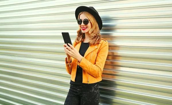 Stylová usměvavá žena s telefonem ve žluté bundě, černý ro — Stock fotografie