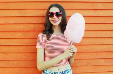 Eğlence parkında ahşap duvarda pamuk şekerle gülümseyen genç bir kadının yaz portresi.