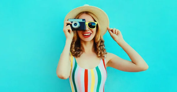 夏の肖像画幸せな笑顔若いです女性とともにレトロカメラ身に着けています夏わら帽子上の青の背景 — ストック写真