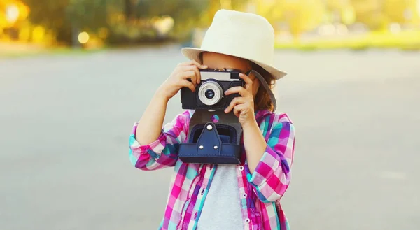 Close up child with retro camera taking picture wearing a summer straw hat outdoors