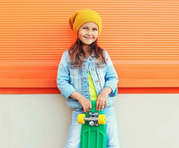 Portret Stylowej Uśmiechniętej Dziewczynki Deskorolką Ulicy Miasta Nad Pomarańczowym Tle — Zdjęcie stockowe