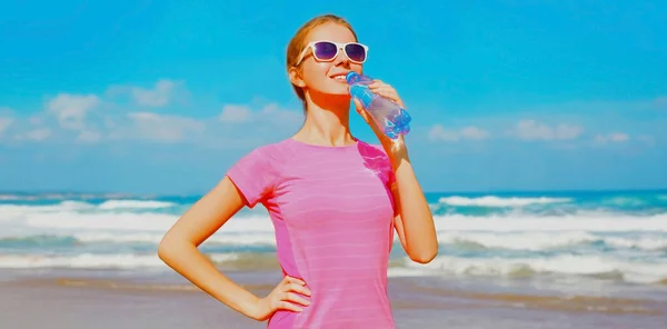 Fitness Mujer Feliz Bebiendo Agua Botella Playa Cerca Del Mar —  Fotos de Stock