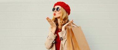 Alışveriş çantasıyla güzel bir kadının sonbahar portresi. Kırmızı dudaklar uçuyor. Güzel bir hava öpücüğü veriyor.