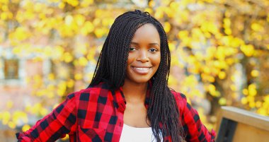 Sonbahar günü güneş gözlüğü takan gülümseyen Afrikalı genç bir kadının portresi.