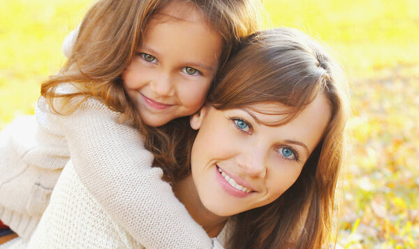 Autumn portrait of happy smiling mother with her daughter child in the park