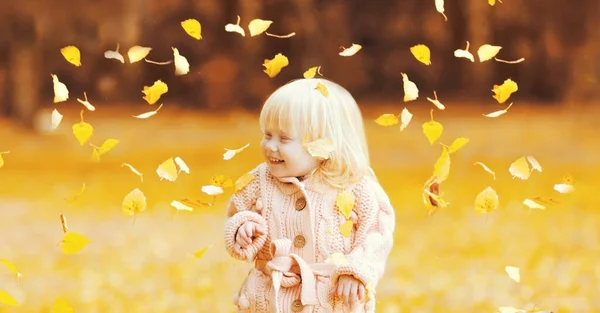秋の公園で黄色の葉を飛んで楽しむ幸せな小さな子供の肖像画 — ストック写真