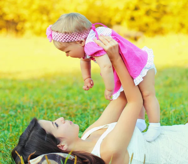 快乐的母亲和小女孩躺在草地上的画像 — 图库照片