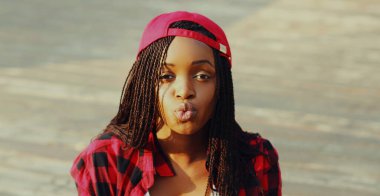 Arka planda rahat bir şekilde gülümseyen Afrikalı bir kadının portresi.