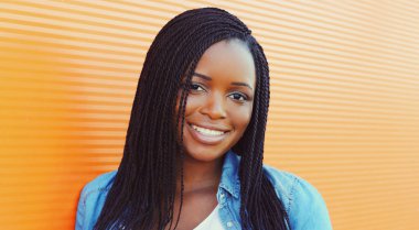 Arka planda rahat bir şekilde gülümseyen Afrikalı bir kadının portresi.