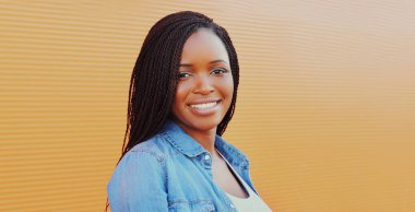 Arka planda rahat bir şekilde gülümseyen Afrikalı bir kadının portresi.