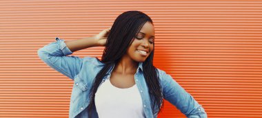 Arka planda rahat bir şekilde gülümseyen Afrikalı bir kadının portresi.