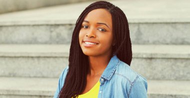 Arka planda rahat bir şekilde gülümseyen Afrikalı bir kadının portresi.