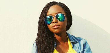 Şehrin arka planında güneş gözlüğü takan Afrikalı genç bir kadının portresi.