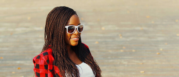 Portrait of happy young smiling african woman wearing a sunglasses in casual over city background