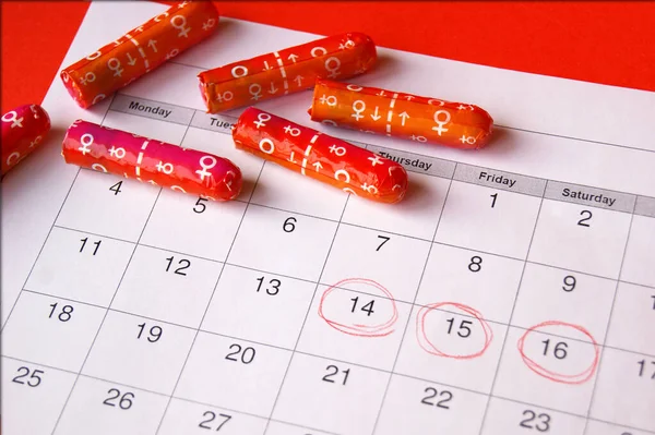 Regl takviminde regl pedleri ve tamponlar kırmızı arkaplanda.