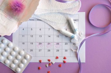 Adet takviminde regl pedi ve tampon ve leylak arkaplanlı.