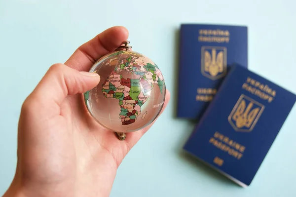 Mano Femenina Sosteniendo Globo Terráqueo Fondo Dos Pasaportes Biométricos Ucranianos — Foto de Stock