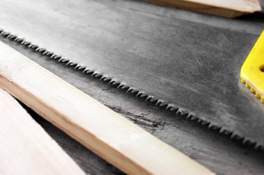 Demir testeresi tahtaya yakın çekim sarı saplı. Tahta bir arka planda ağaç kesmek için el testeresi. Marangozluk için el aletleri.