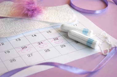 Adet takviminde regl pedi ve tampon ve leylak arkaplanlı.