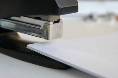 Belgeleri olan klasik bir siyah ofis zımbası. Çalışma alanında..