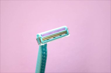 Özenle seçilmiş tek kullanımlık tıraş makinesi odaklı yakın plan görüntüsü soyut pembe arka planda izole edilmiş. Tıraş bıçağı ve cilt bakımı konseptiyle kadın ve erkek tüy dökümü tedavisi. Epilasyon tüy dökücü..