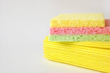 Bulaşık yıkamak, banyoyu temizlemek ve diğer ev ihtiyaçlarını karşılamak için parlak renkli süngerler birbirinin üstünde yer almaktadır. İzole edilmiş. Yakın plan.