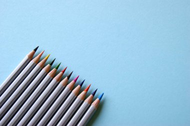 Açık mavi arkaplanda birçok renkli kalem bulunur. Sanat konsepti