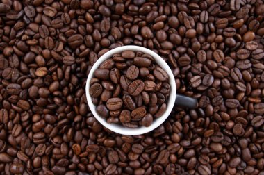 Koyu renkli taze kavrulmuş kahverengi kahve çekirdeklerinin farklı bir karışımı. Kahve taneleriyle dolu bir fincan. Doğal kahve arkaplanı çizimi