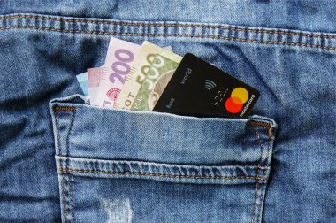 KHARKOV, UKRAINE - 19 Şubat 2020: Ukrayna banknotları ve kot pantolonun arka cebinde bir kredi kartı ana kartı. Temassız elektronik ödeme kavramı.